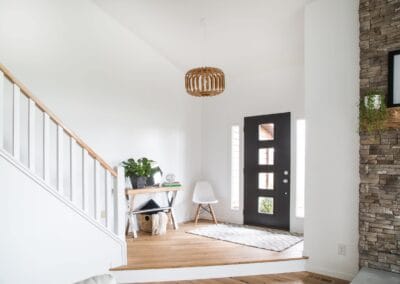 This custom built home features a two tier foyer that leads into the living room. This home features white walls and a black door with small glass windows for contrast.