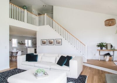 A white living room featuring a wooden banister to the 2nd story.