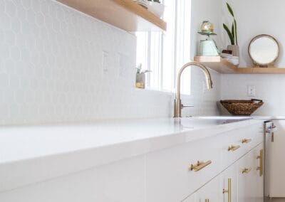 A white kitchen with gold hardware and open shelving.