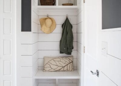 a white and navy mudroom featuring wainscoating walls.