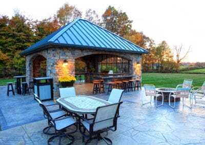 A covered patio featuring tile flooring, and a full built in kitchen with a grill, and sink.