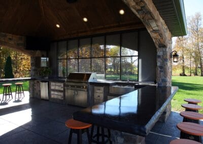 A covered patio featuring tile flooring, and a full built in kitchen with a grill, and sink.