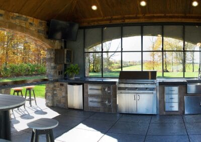 A covered patio featuring tile flooring, and a full built in kitchen with a grill, and sink.
