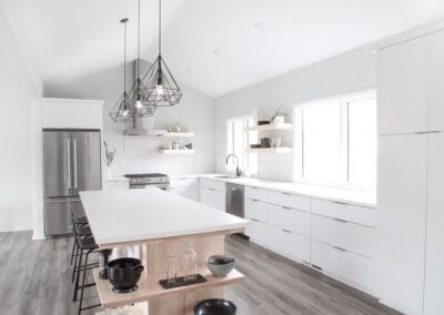 A chic custom built home featuring cool wood floors and white walls for contrast. This home has an open concept floor plan between the kitchen and living room.