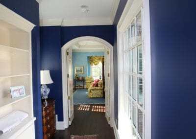 A custom built home featuring a royal blue hallway which white doorframes and window frames.
