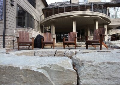 A custom built two story deck and patio. The patio features a natural stone bonfire set up with a view.