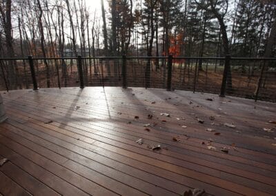 A custom built deck with a view. The deck features brown wood and black cable railings.