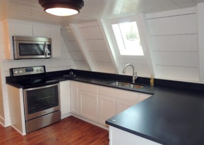 This kitchen features white cabinets and walls, with black counter tops for contrast.