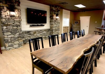 A rustic style showroom featuring stone accent walls and a natural wood dining table.