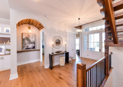 A front foyer with a round chandelier. A hall way off of the foyer has a wooden coved ceiling.