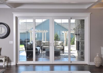 French sliding doors leading out to a finished patio that features black furniture, an outdoor fireplace, and white pergolas.
