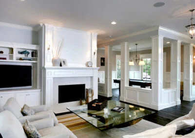 A timeless living room featuring wainscoting columns around a built-in fireplace, and a glass coffee table.