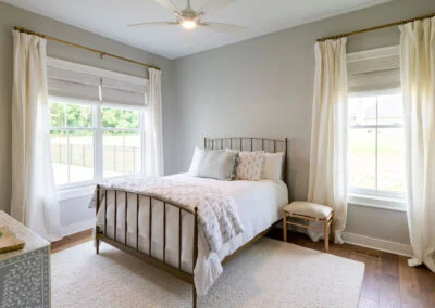 A bedroom featuring gold furniture, white curtains, and a white rug.