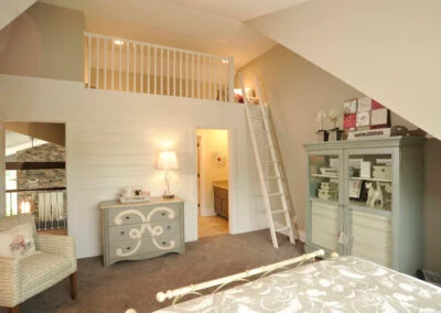 A children's room featuring a built-in loft bed and soft green furniture with white walls.