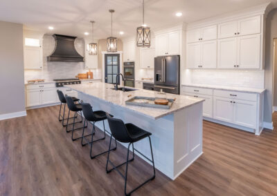 a modern style kitchen with white and grey marble countertops, steel appliances, and charcoal hardware.
