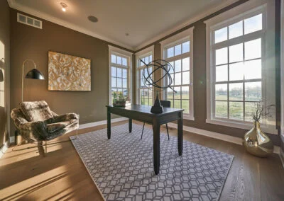 an office with brown walls, wood floors, and a geometric-patterned rug.