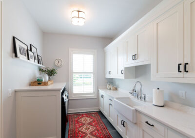White laundry room with a basin sink. There is a red runner for a pop of color.