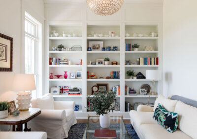 A contemporary, custom-built book shelf, used as an accent wall in a white living room.