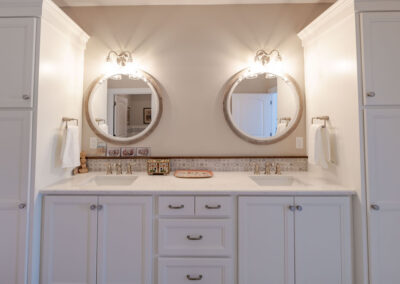 Custom Jack & Jill bathroom featuring white counter tops & cabinets, and gold hardware.