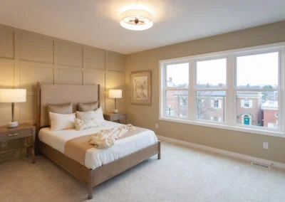 A light tan bedroom with a square paneled accent wall.