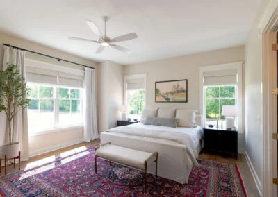 An egg-shell painted bedroom, featuring a red rug for a pop of color.