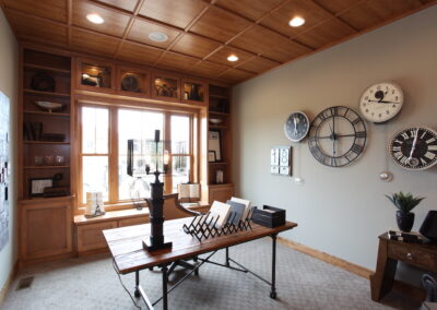 Custom built shelving around a framing a bay window. This room is carpeted with a light gray carpet, and has light tan, painted walls.