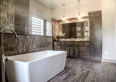 custmo built bathroom with brown tiling, and brown cabinets, as well as a stand alone white tub