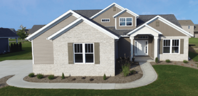 Large home with grey stone siding with a concrete walkway leading to the front door. 